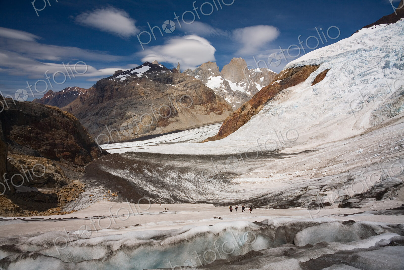 Several hikers on a glacier and Fitz Roy loom in the background. Los Glaciares…