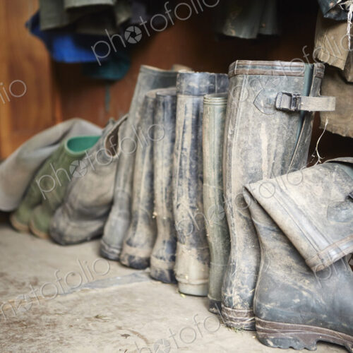 Several pairs of muddy wellington boots on a stone floor. Several pairs of muddy wellington boots on a stone floor.