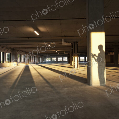 Shadow of a business man cast on a central post of a large empty raw office space. Shadow of a business man cast on a central post of a large empty raw office space.