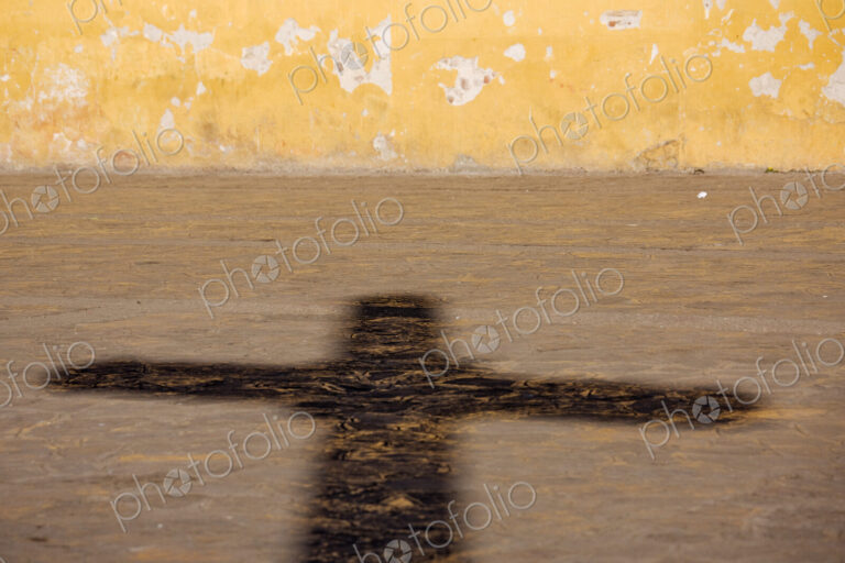 Shadow of a crucifix on a street pavement.
