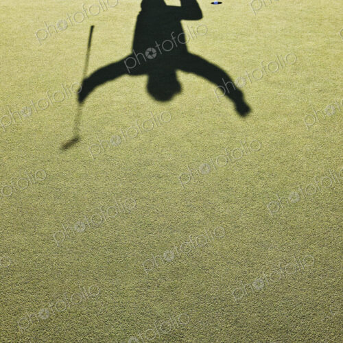 Shadow of a golfer jumping after hitting a great golf shot.