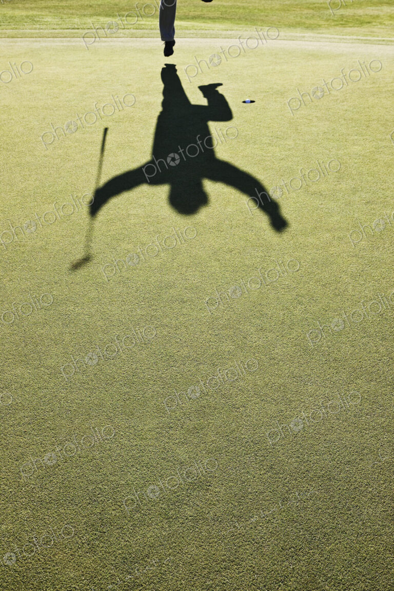 Shadow of a golfer jumping after hitting a great golf shot.