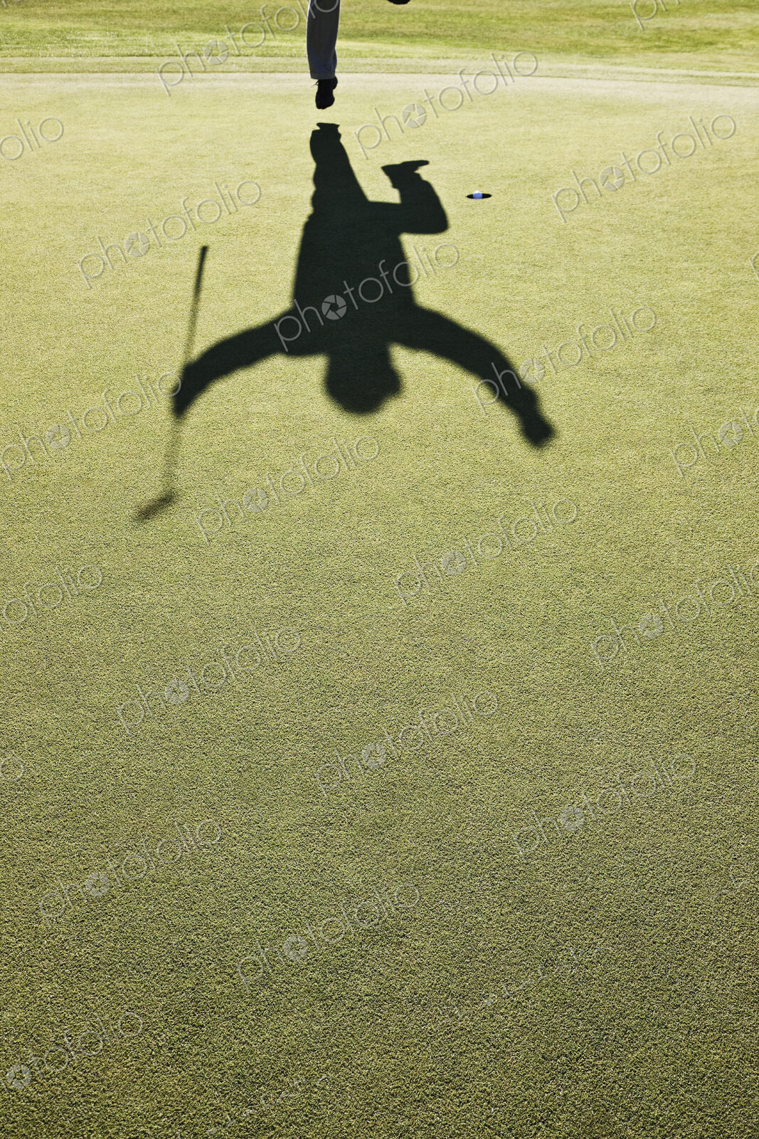 Shadow of a golfer jumping after hitting a great golf shot.