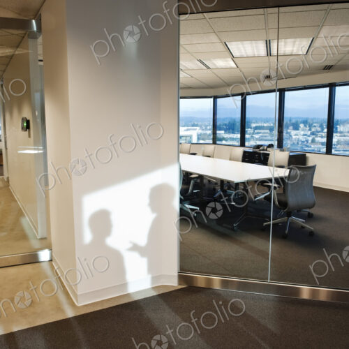 Shadows of two business people on the wall outside of a company conference room..