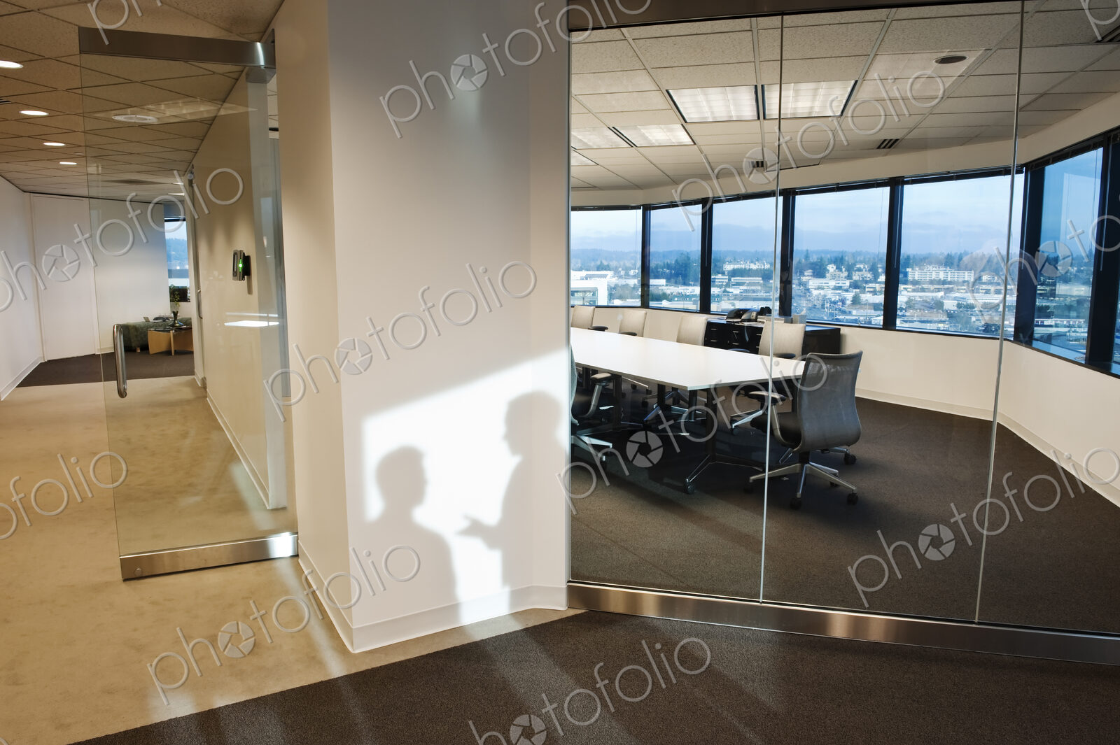Shadows of two business people on the wall outside of a company conference room..