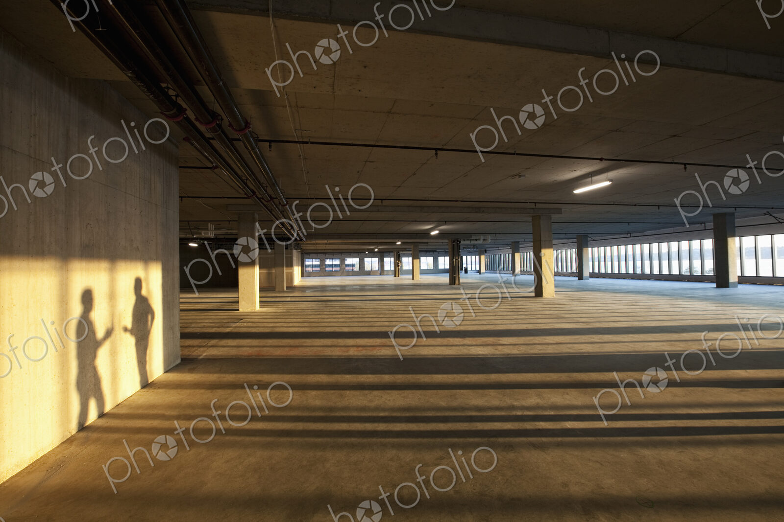 Shadows of two men shaking hands on the wall of an empty raw business space.