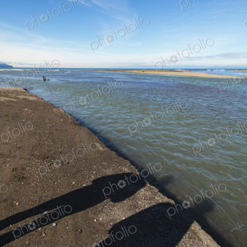 Shadows of two people on beach sand alongside the Elwha River, Port Angeles, WA USA