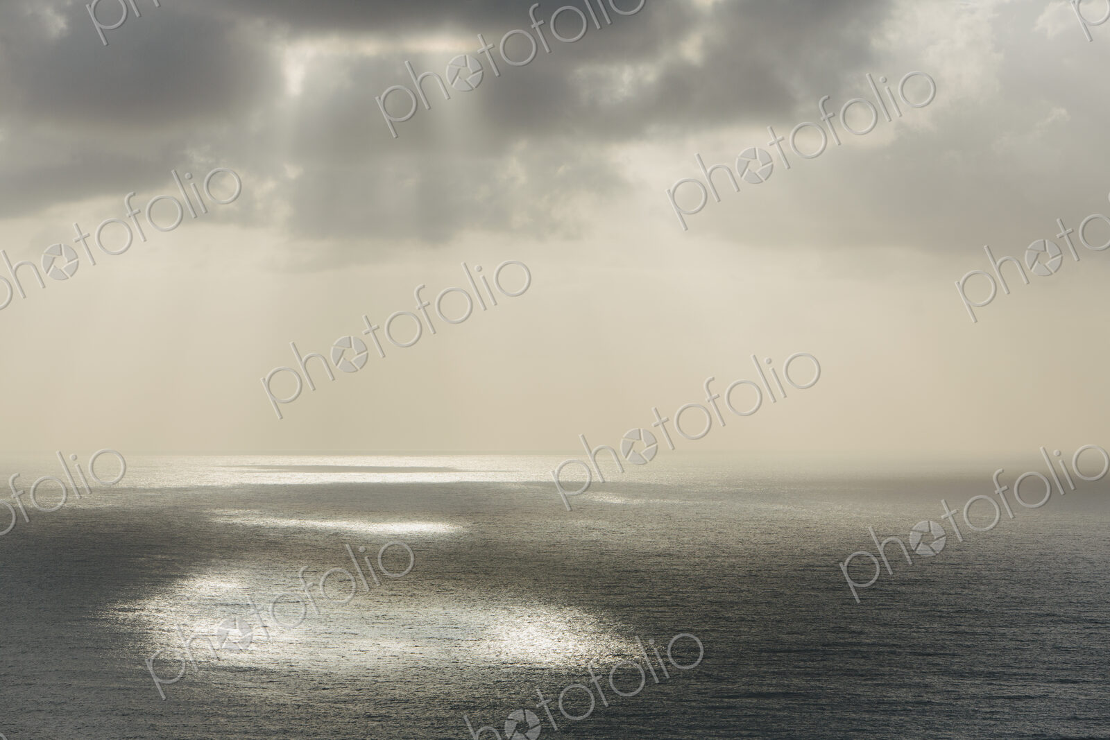 Shafts of sunlight shining through cloud and a view over the Pacific Ocean, at…