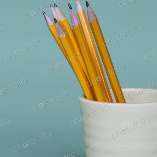 Sharpened pencils in cup, on a blue background.