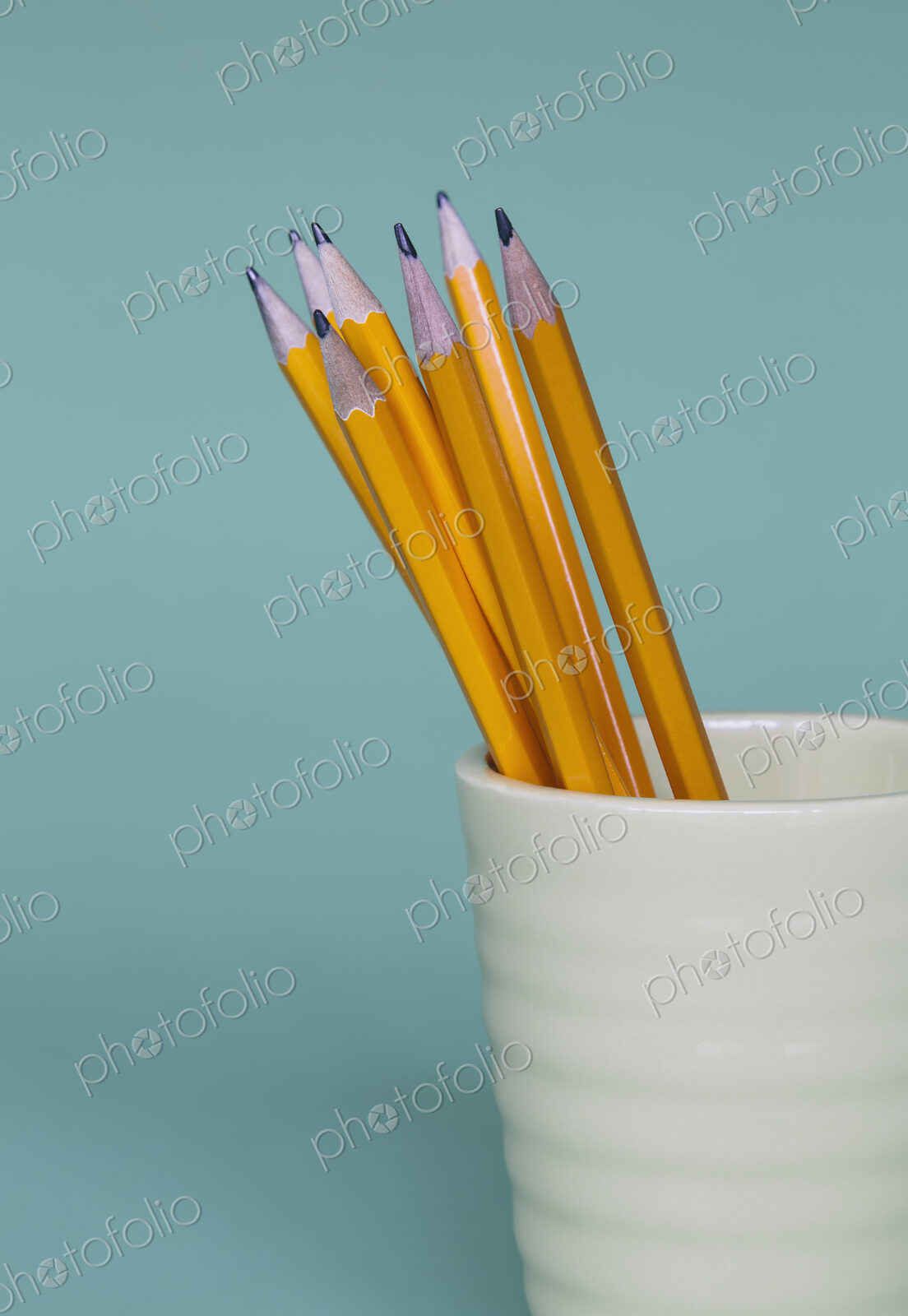 Sharpened pencils in cup, on a blue background.
