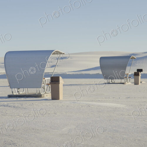 Shelters and trash bins among gleaming white sand dunes.