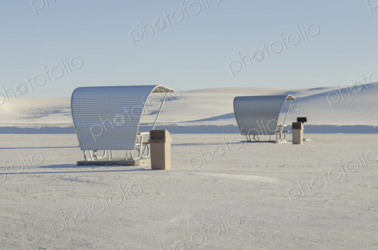 Shelters and trash bins among gleaming white sand dunes.