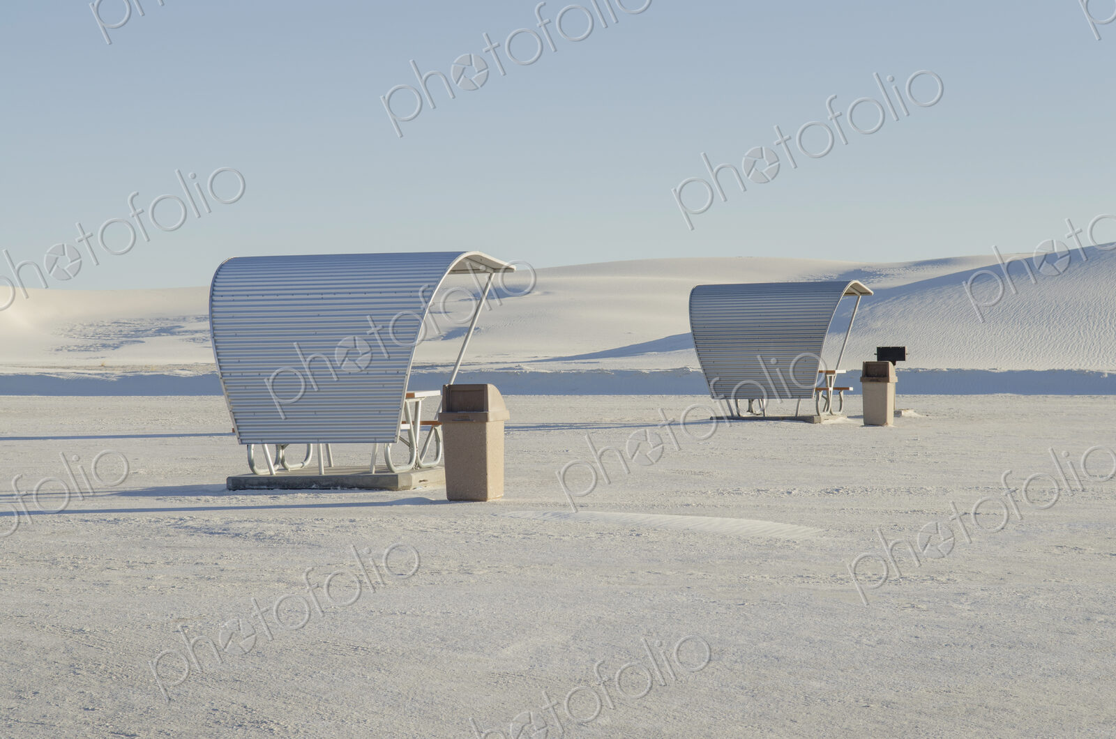 Shelters and trash bins among gleaming white sand dunes.