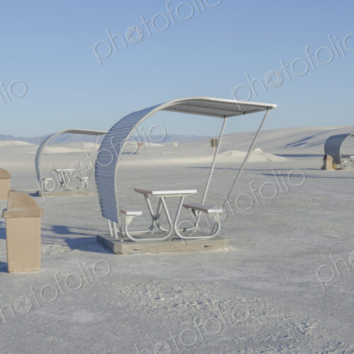 Shelters and trash bins among gleaming white sand dunes.
