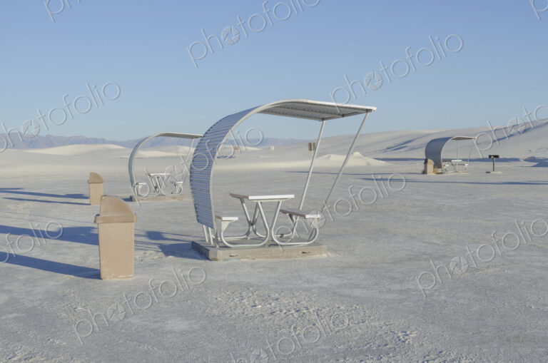 Shelters and trash bins among gleaming white sand dunes.