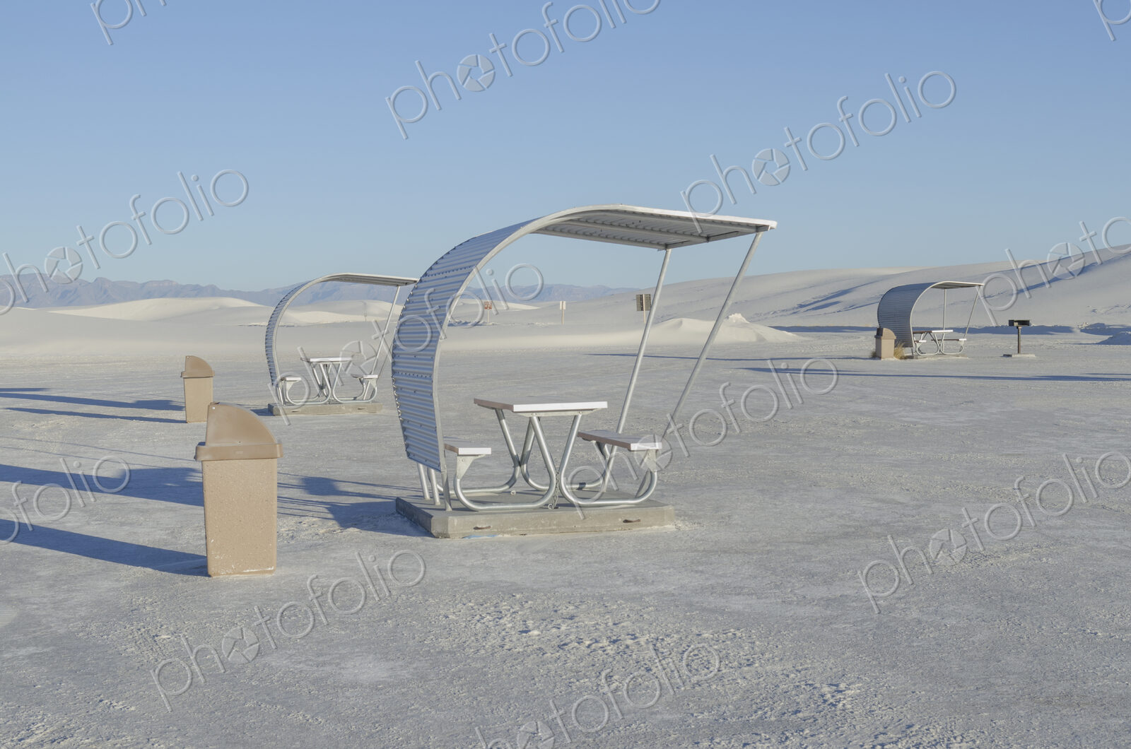 Shelters and trash bins among gleaming white sand dunes.