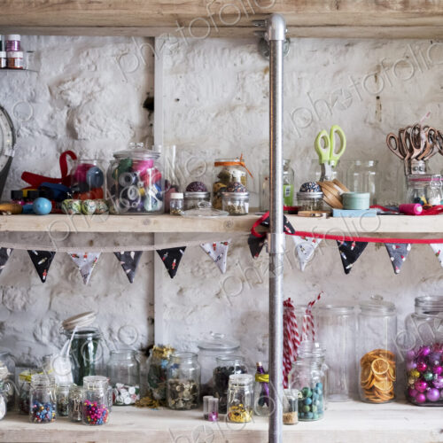 Shelves, stock of scissors and colourful beads in glass jars, for sewing and craft. Shelves, stock of scissors and colourful beads in glass jars, for sewing and craft.