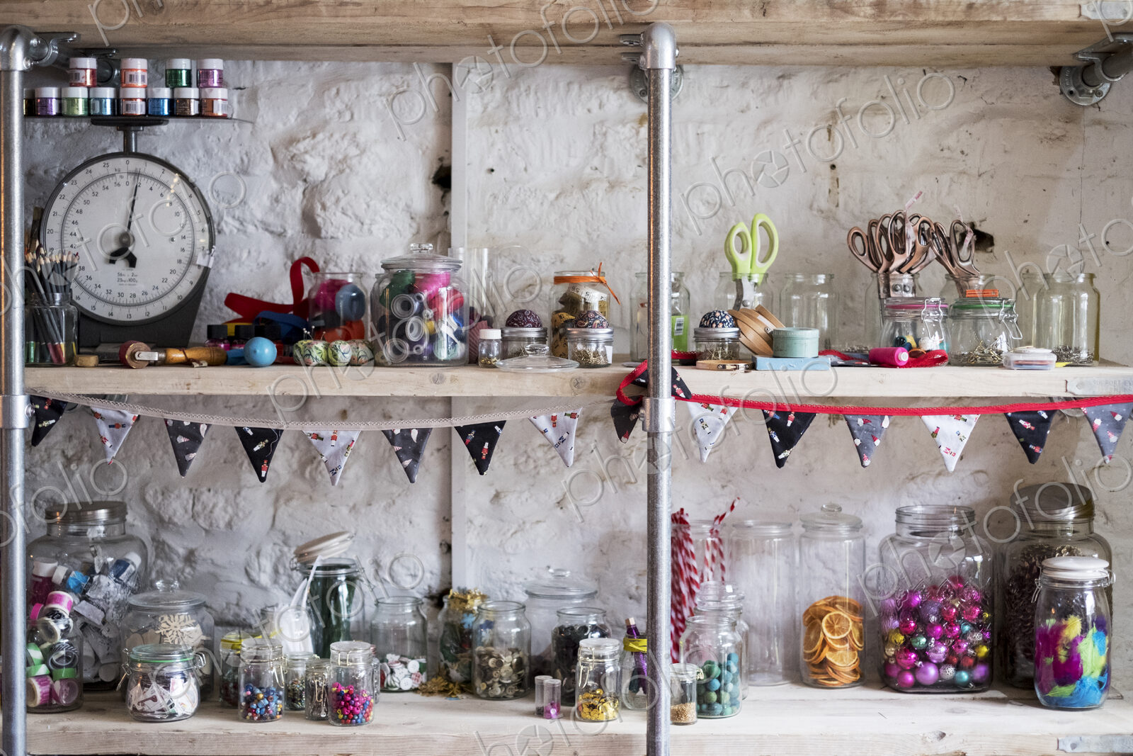 Shelves, stock of scissors and colourful beads in glass jars, for sewing and craft.
