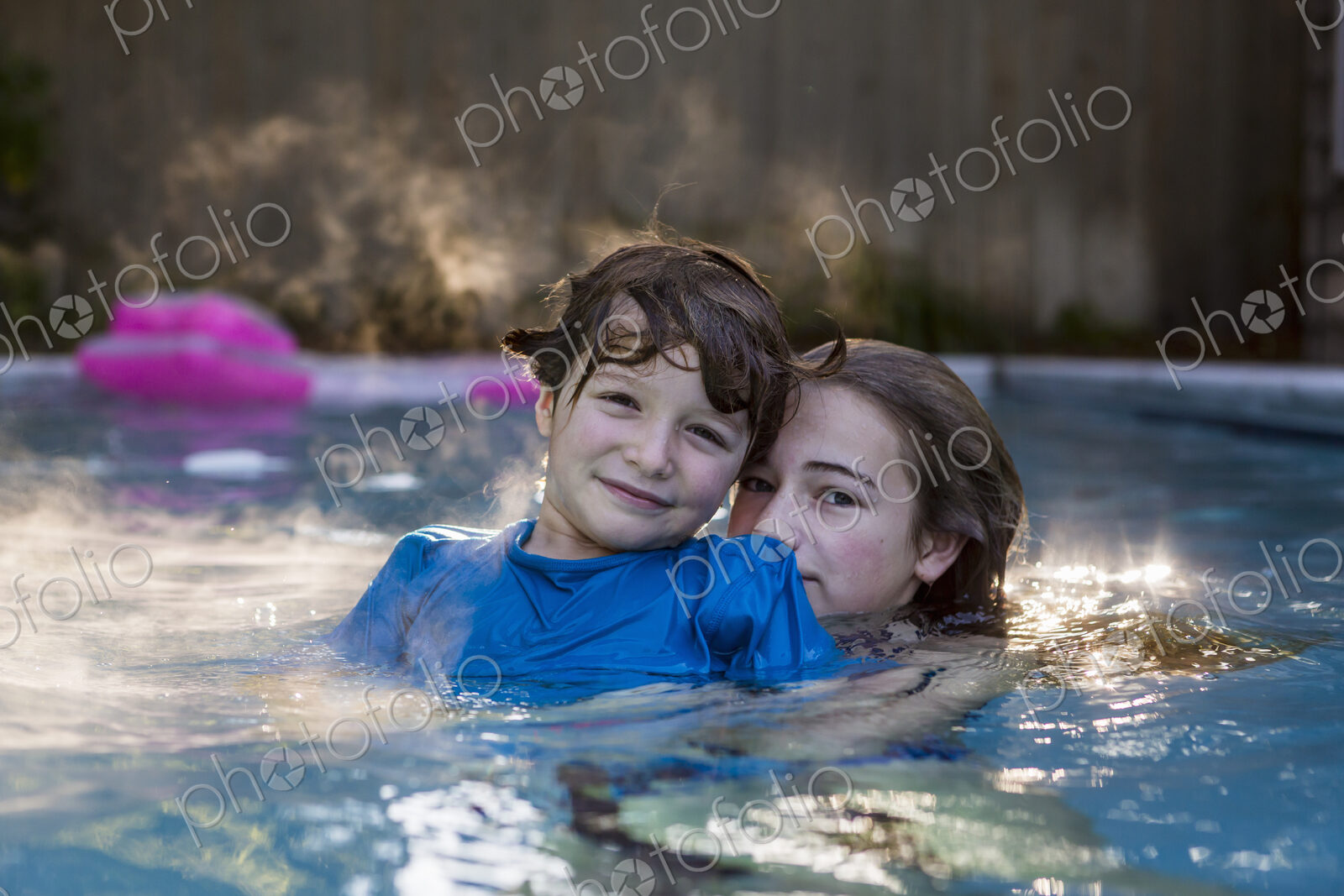 Siblings playing in pool in early morning light