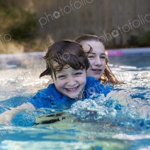 Siblings playing in pool in early morning light Siblings playing in pool in early morning light