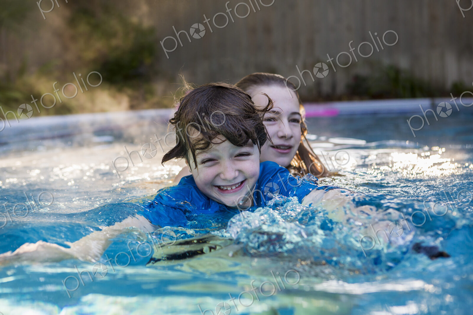Siblings playing in pool in early morning light
