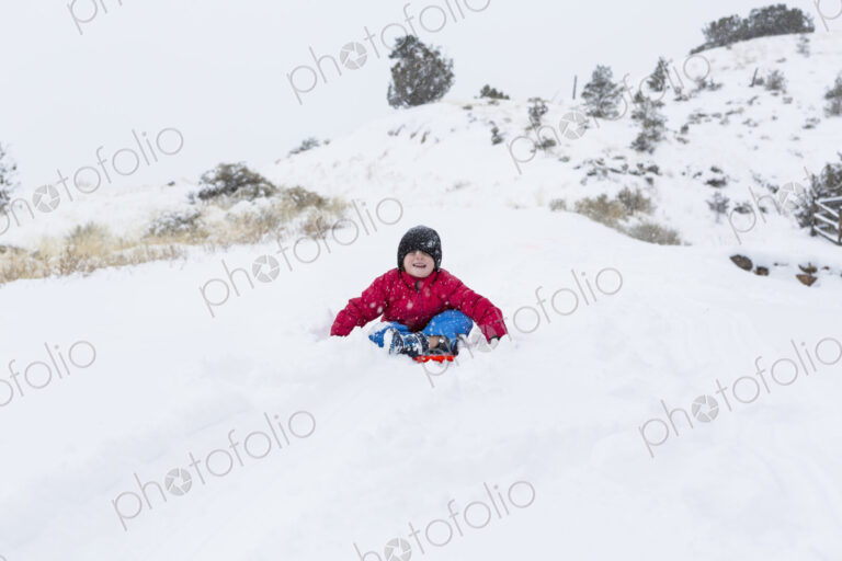 Siblings sledding down hill