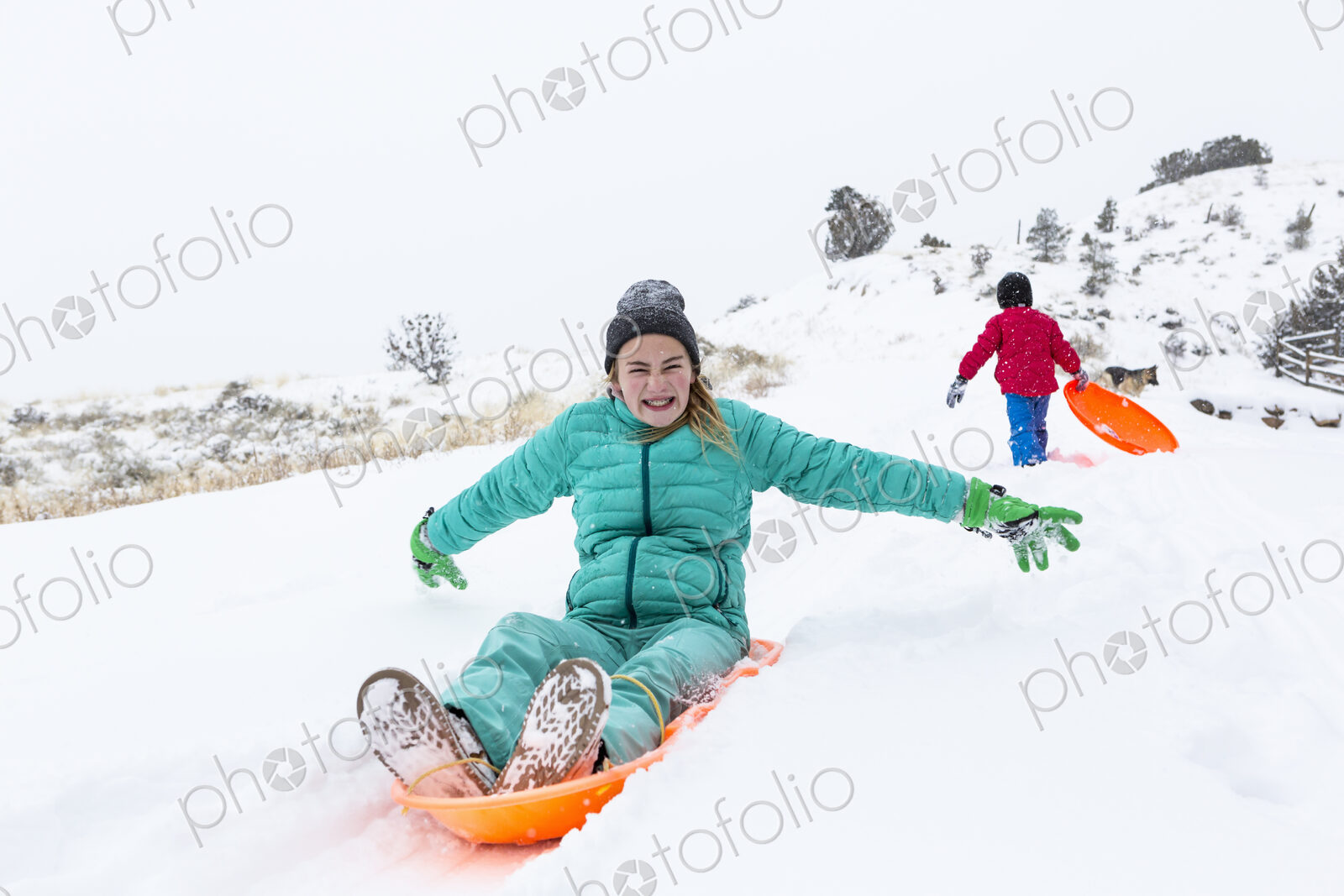Siblings sledding down hill