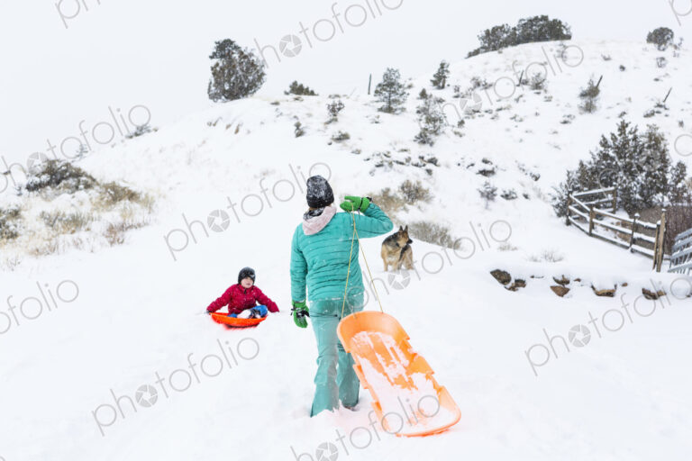 Siblings sledding down hill