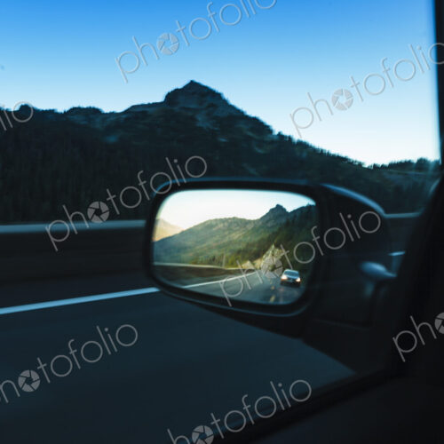 Side mirror of a car passing through mountainous landscape, the view ahead and behind. Side mirror of a car passing through mountainous landscape, the view ahead and behind.