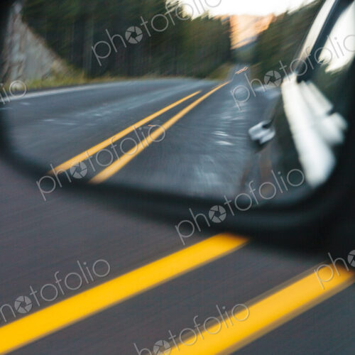 Side mirror view of a mountain highway, the road behind the car. Side mirror view of a mountain highway, the road behind the car.