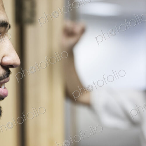 Side view closeup of a black businessman standing and talking in his office space. Side view closeup of a black businessman standing and talking in his office space.