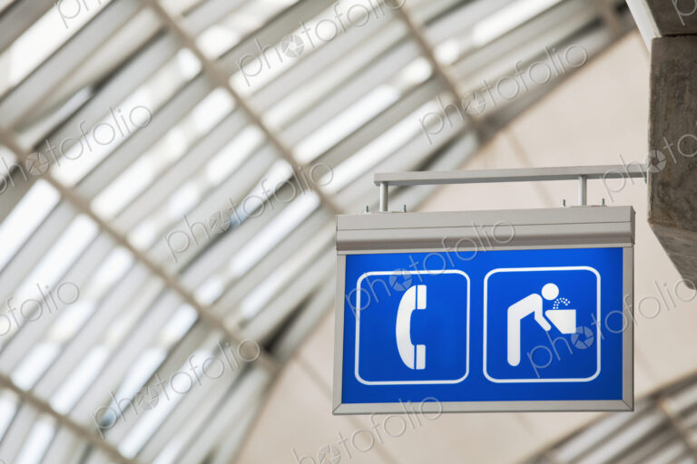 Sign for telephone and drinking fountain in large public building.