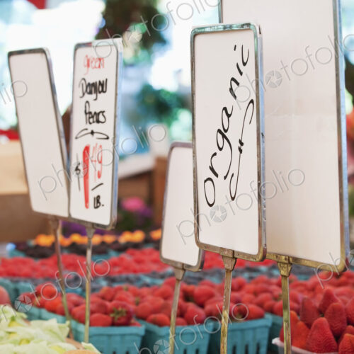 Signs and organic produce at vegetable stall in market. Signs and organic produce at vegetable stall in market.