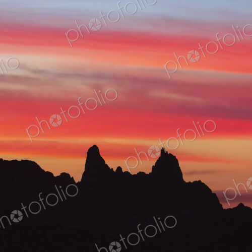 Silhouette of Mule Ears, two peaks at sunrise below a glowing sky, Big Bend National Park.