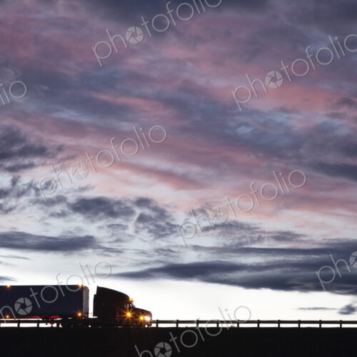 Silhouette of a commercial truck driving on a highway at sunset. Silhouette of a commercial truck driving on a highway at sunset.