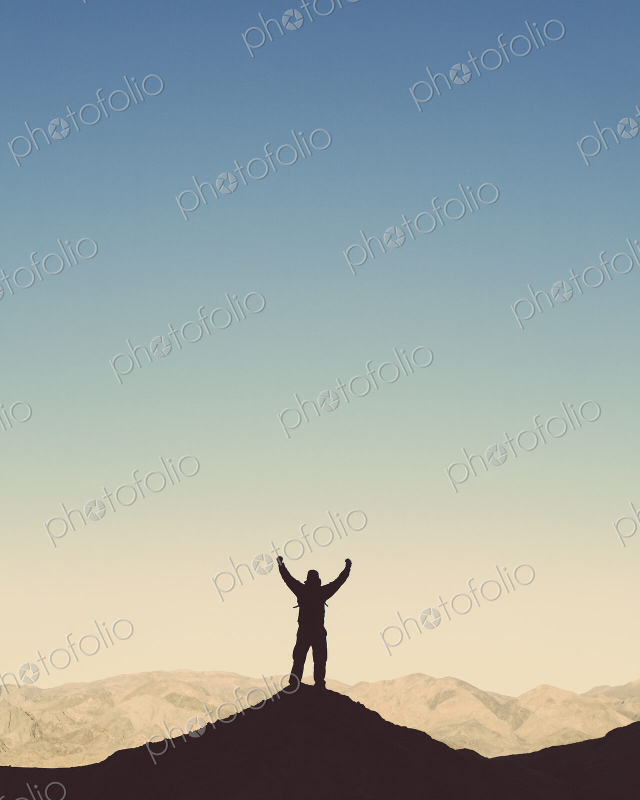 Silhouette of a male hiker wearing a backpack and standing on a hilltop in Death…