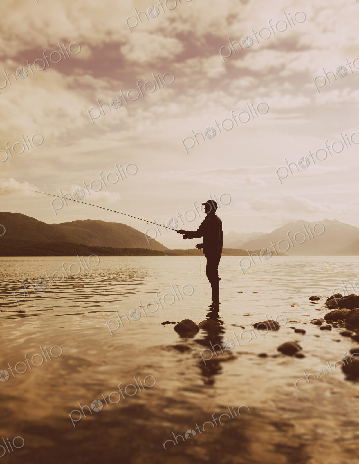 Silhouette of a man flyfishing in calm waters on the Waschusett inlet in Glacier Bay…