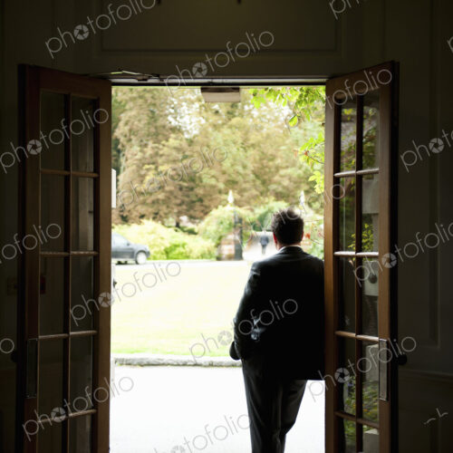 Silhouette of a man standing in a doorway leaning against the door frame, looking out… Silhouette of a man standing in a doorway leaning against the door frame, looking out…