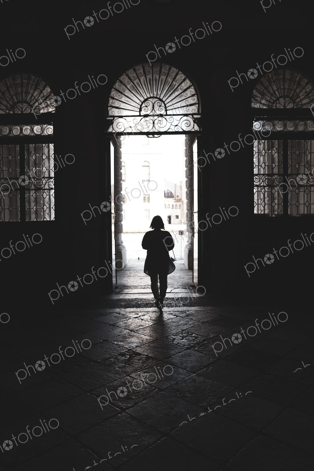 Silhouette of a woman walking through an arched doorway in Venice, Veneto, Italy.