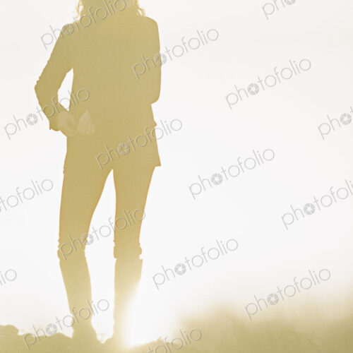 Silhouette of a woman with long curly hair standing in a sunlit landscape. Silhouette of a woman with long curly hair standing in a sunlit landscape.