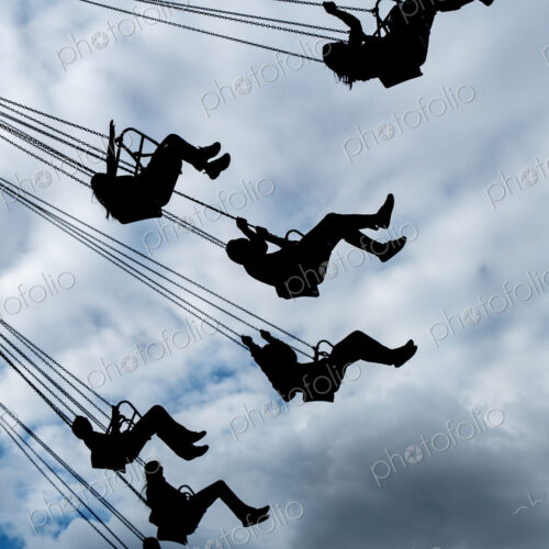 Silhouette of people riding chair swing under cloudy sky Silhouette of people riding chair swing under cloudy sky