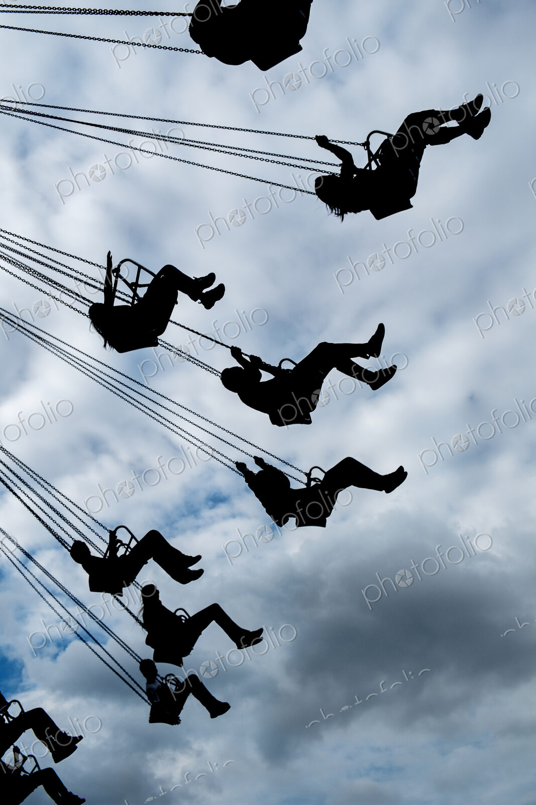 Silhouette of people riding chair swing under cloudy sky