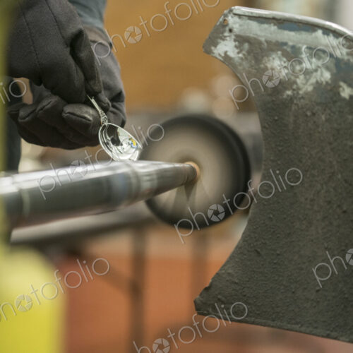 Silversmith polishing silver spoon using a small rotating disc on a machine. Silversmith polishing silver spoon using a small rotating disc on a machine.