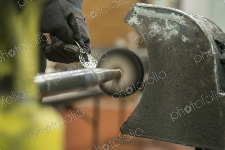 Silversmith polishing silver spoon using a small rotating disc on a machine.