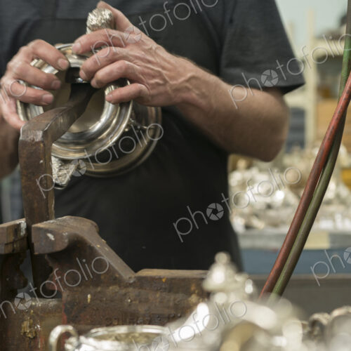 Silversmith restoring silver cup in workshop. Silversmith restoring silver cup in workshop.