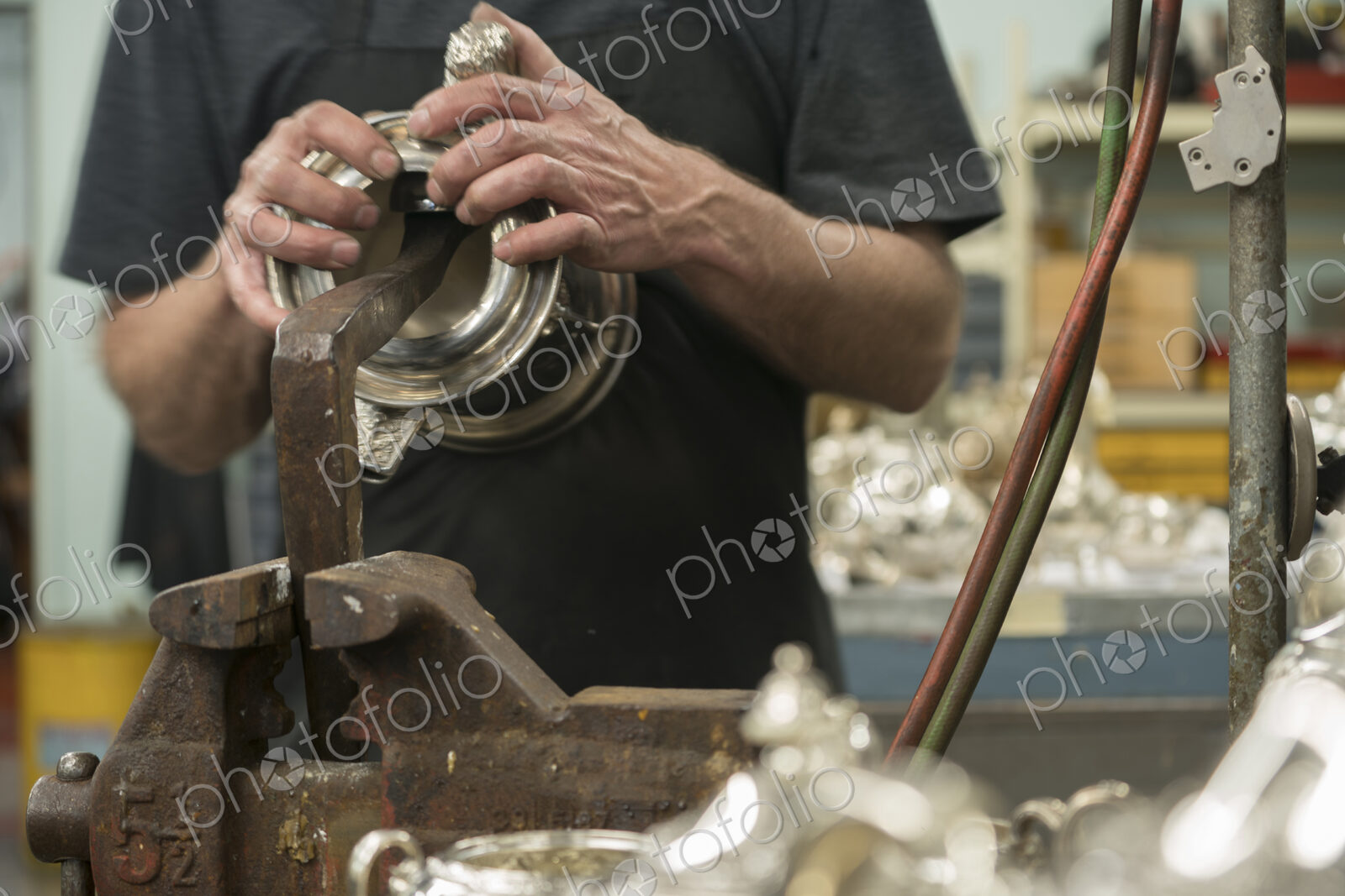 Silversmith restoring silver cup in workshop.