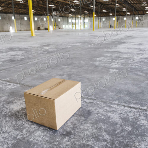 Single cardboard box in the middle of a new empty warehouse space. Single cardboard box in the middle of a new empty warehouse space.