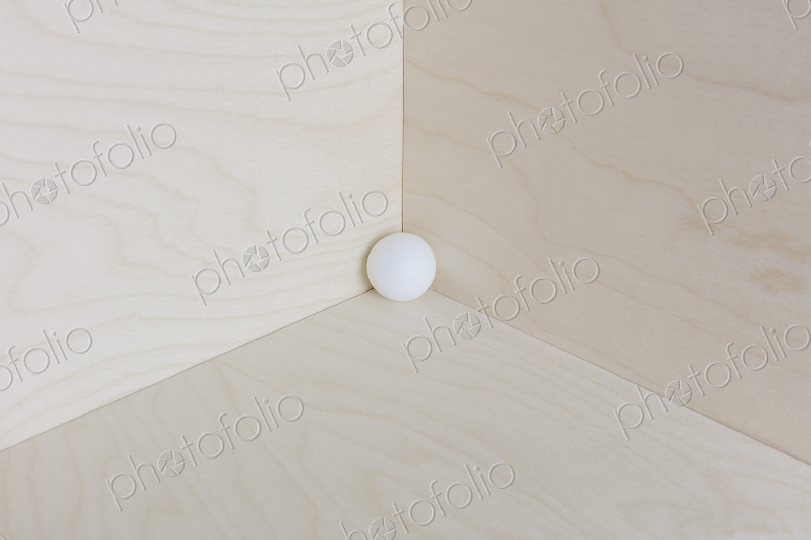 Single white ball in corner of a wooden box.