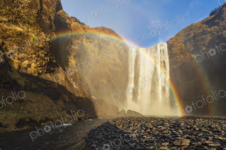 Skagafoss waterfall, cliffs and a Double Rainbow, a cascade falling into a pool.