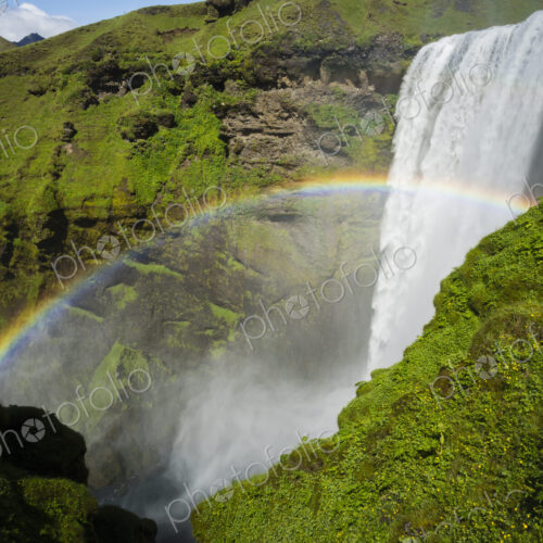 Skogafoss waterfall, a cascade over a sheer cliff, and a rainbow in the mist.